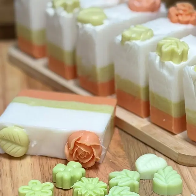 Barras em camadas creme, verde e laranja com flores e suculentas no topo