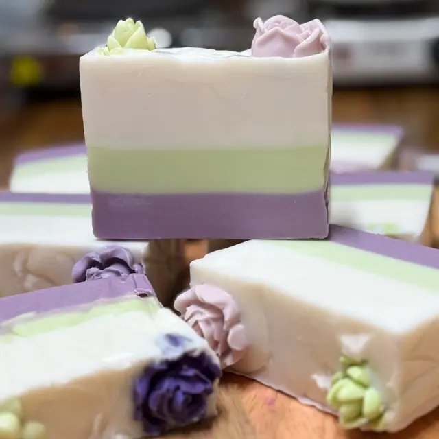 Barras em camadas creme, verde e lilás com flores no topo