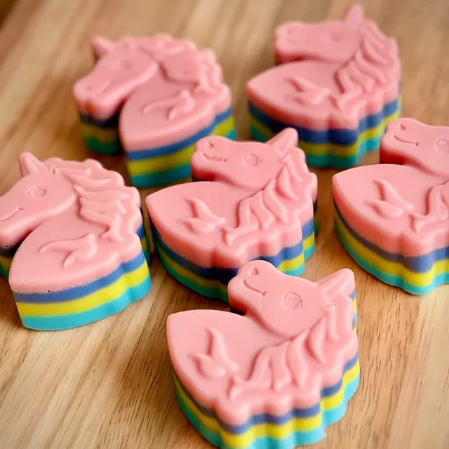 Sabonetes de unicórnio rosa em camadas de azul, amarelo e lilás