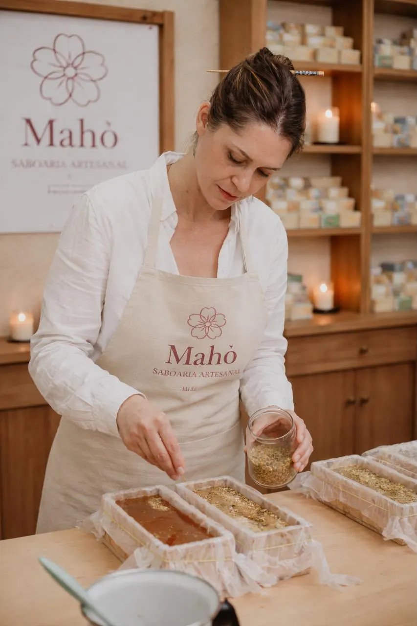 Rosilaini, de avental Mahō, no ateliê, fazendo sabonete